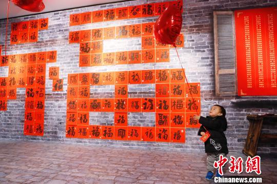 孩子在“福”字墻前玩耍著。 殷立勤 攝